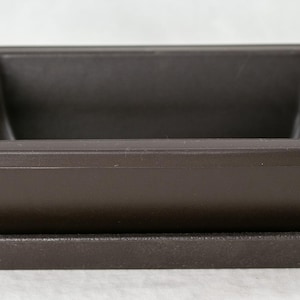 May include: A brown plastic rectangular planter with a matching tray. The planter is designed to hold plants or flowers.