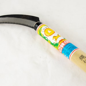 May include: A curved, serrated blade with a wooden handle. The handle is wrapped in a colorful label with Japanese text and a picture of a horse. The text on the label reads "如来寺"