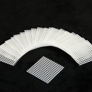 May include: A set of 20 white plastic mesh squares, arranged in a semi-circle with one square in the center. The squares are approximately 2 inches by 2 inches.