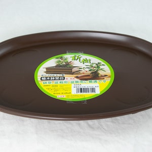 May include: A brown oval plastic tray for plant pots. The tray has a label that reads "ポリプロピレン製 植木鉢受台 盆栽、盆景用に最適です 535A エンデック".