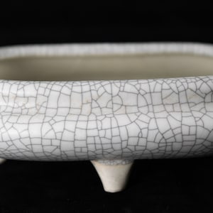 May include: White ceramic bonsai pot with a crackled glaze and four small feet.