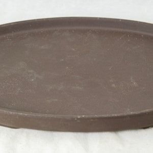 May include: A brown oval ceramic saucer for a plant pot.