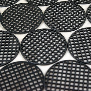 May include: A collection of black, round, plastic plant pot saucers with a grid pattern. The saucers are arranged in a close-up shot, showcasing their uniform design and texture. The grid pattern allows for drainage and air circulation.
