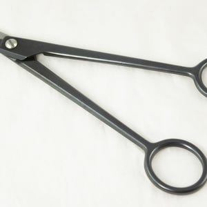 May include: A pair of black surgical scissors with a silver handle and a sharp point.