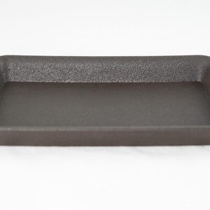 May include: A dark gray plastic rectangular tray with a textured surface.