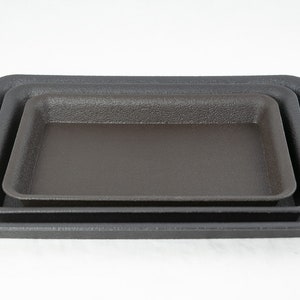 May include: Three black plastic trays of varying sizes, stacked on top of each other.