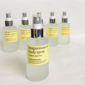 May include: Six clear glass spray bottles with silver tops. The bottles are filled with a clear liquid and have a yellow label with the text "magnesium oil body spray relieve and rest mollyandfrankie handmade in Byron Bay Australia www.mollyandfrankie.com.au"