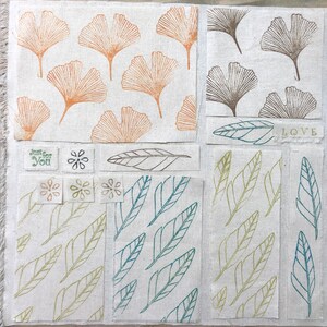 May include: A fabric collage featuring a variety of leaf patterns. The top left section displays a repeating pattern of orange ginkgo leaves. The top right section shows a repeating pattern of brown ginkgo leaves. The bottom left section features a repeating pattern of green leaves. The bottom right section features a repeating pattern of green and blue leaves. The centre section features a single brown leaf and the text "Just for You". The top centre section features the text "LOVE".