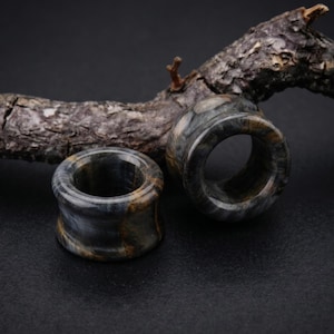 Peut inclure: Une paire d'écarteurs d'oreilles circulaires fabriqués en pierre d'œil de tigre bleue et dorée polie. Les écarteurs présentent un design en selle concave et lisse avec une finition brillante, mettant en valeur les bandes naturelles.