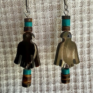 May include: A pair of dangle earrings featuring a carved dark brown bird-shaped pendant suspended from silver-toned hooks. Each earring is accented with alternating cylindrical beads in turquoise blue and dark brown wood-toned material.