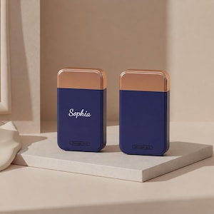 Puede incluir: Dos cajas de almacenamiento azul marino con tapas de oro rosa. Una caja tiene el nombre "Sophia" en escritura blanca. El texto "Storage Box" está en la parte inferior de cada caja.