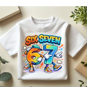 Op de afbeelding: Wit T-shirt met de tekst "SIX SEVEN" in een kleurrijk, cartoonachtig ontwerp. De cijfers 6 en 7 zijn gepersonifieerd met armen, benen en schoenen. Het cijfer 6 is oranje en geel, terwijl het cijfer 7 blauw is.