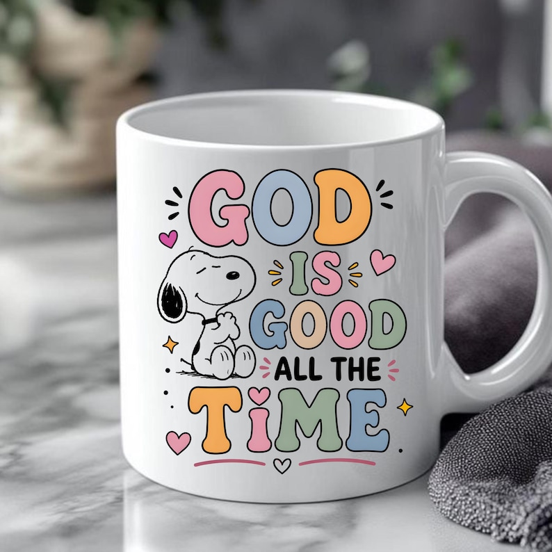 Puede incluir: Taza de cer&aacute;mica blanca con Snoopy y la frase "GOD IS GOOD ALL THE TIME" en letras de colores. La taza tiene un asa curva y es adecuada para bebidas fr&iacute;as o calientes.