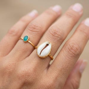 Puede incluir: Una taza de cerámica blanca con un asa negra y el texto "But First, Coffee" en negrita negra. La taza está sobre una superficie de madera. La taza mide aproximadamente 10 cm de alto.