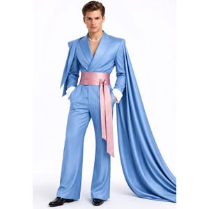 May include: A light blue suit featuring a double-breasted jacket with long, flowing cape-like sleeves and wide-leg trousers. The ensemble is cinched at the waist with a wide, satin-finish dusty pink sash that ties in the front with long, hanging ends.