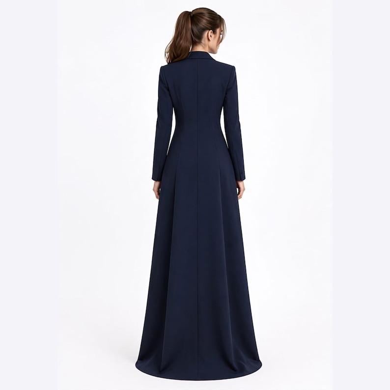 May include: A floor-length navy blue coat dress featuring a structured collar, long sleeves, and a fitted bodice that transitions into a flared, full-length skirt. The garment is shown from the back, displaying a clean, solid-coloured design.