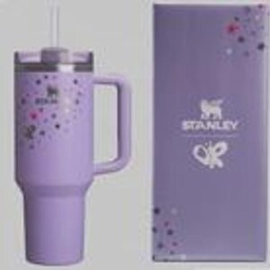 K&ouml;nnte beinhalten: Ein lavendelfarbener Stanley-Becher mit Griff, verziert mit bunten Punkten und einem Schmetterlingsdesign. Der Becher hat einen Deckel und einen Strohhalm. Eine passende lavendelfarbene Box mit dem Stanley-Logo und Schmetterlingsdesign befindet sich neben dem Becher.