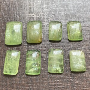 May include: Eight green, rectangular, polished gemstones with a translucent, glassy finish. The stones have a light green color and a subtle, striated pattern.