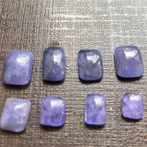 May include: Eight small, rectangular, purple gemstones with a light, iridescent sheen.