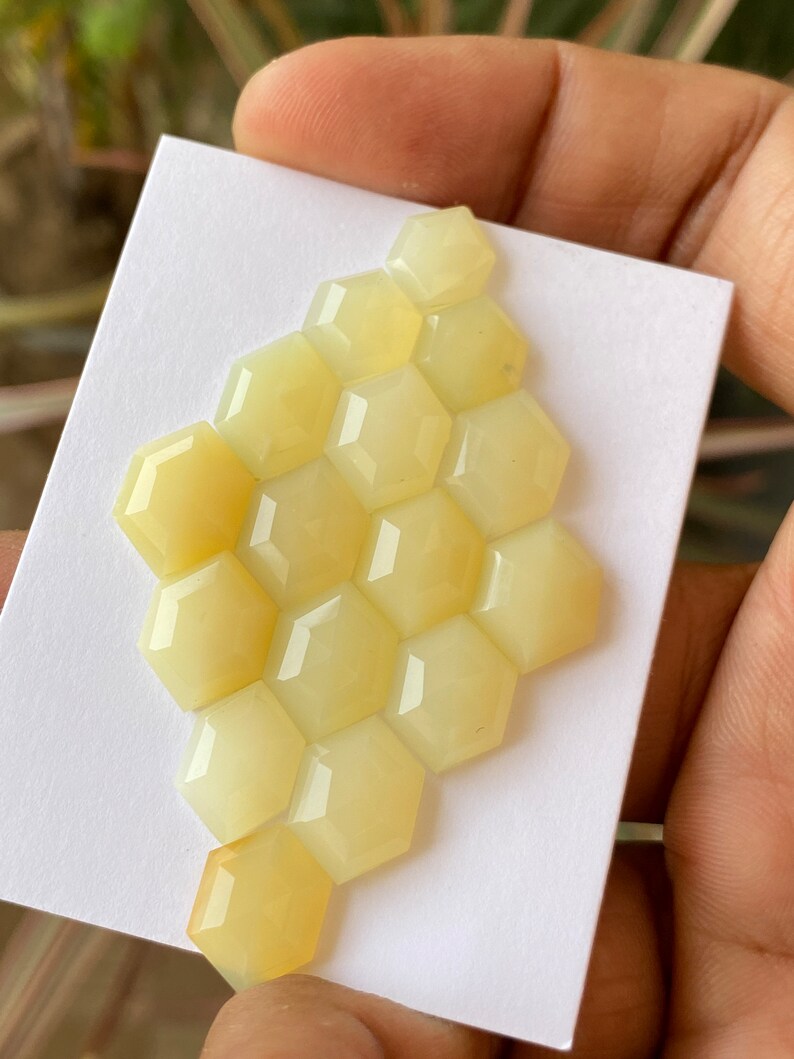 Peut inclure: Un groupe de 12 cabochons hexagonaux de couleur jaune dispos&eacute;s en forme de nid d'abeille. Les cabochons sont lisses et polis.