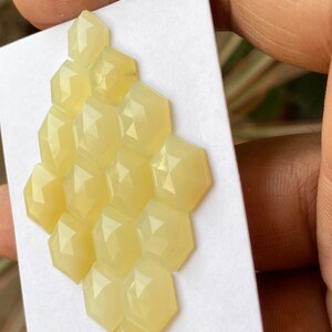 Peut inclure: Un groupe de 14 pierres pr&eacute;cieuses cabochon hexagonales jaune p&acirc;le dispos&eacute;es en nid d'abeille sur un fond blanc.