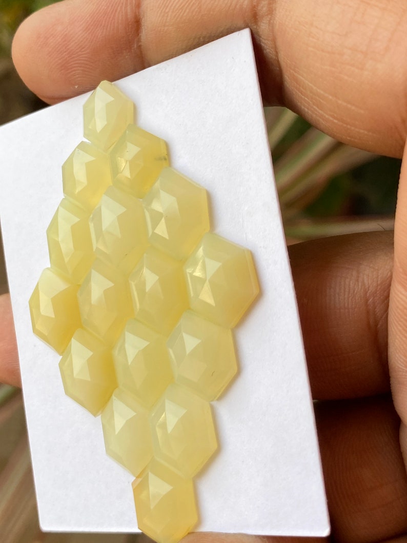 Peut inclure: Un groupe de 14 pierres pr&eacute;cieuses cabochon hexagonales jaune p&acirc;le dispos&eacute;es en nid d'abeille sur un fond blanc.