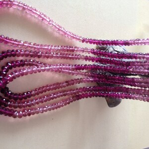 May include: Multiple strands of faceted gemstone beads in shades of pink and purple. The beads are strung together, creating a cascading effect. The colour gradient ranges from light pink to deep magenta.