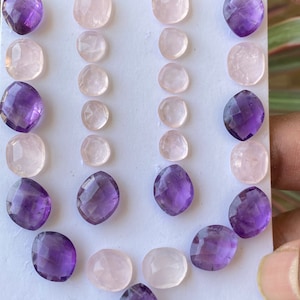 Könnte beinhalten: Eine Sammlung von 18 facettierten Edelstein-Cabochons, darunter Amethyst und Rosenquarz. Die Steine sind in drei Reihen auf einem weißen Hintergrund angeordnet.