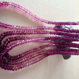 May include: Multiple strands of faceted gemstone beads in shades of pink and purple. The beads are strung to create necklaces, with a colour gradient from light pink to deep purple. The necklaces are draped, displaying the colour transition.