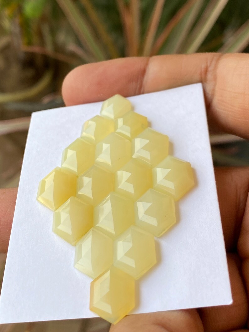 Peut inclure: Un groupe de 12 cabochons hexagonaux facet&eacute;s de couleur jaune dispos&eacute;s en nid d'abeille sur un fond blanc.