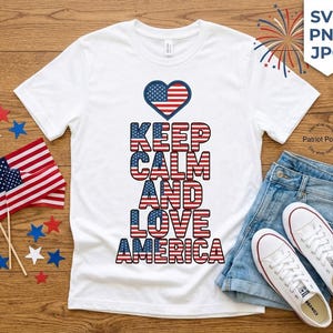 May include: White t-shirt with the text "KEEP CALM AND LOVE AMERICA" in red, white, and blue. The design includes a heart-shaped American flag. The shirt is paired with denim shorts and white sneakers, with small American flags and star-shaped decorations.