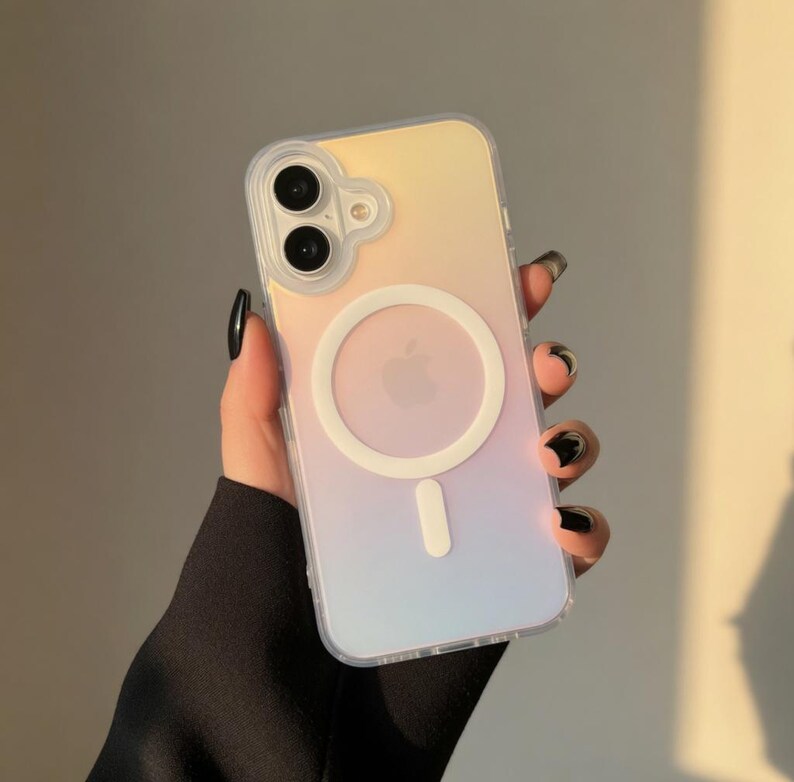 May include: A clear phone case with a pastel gradient of yellow, pink, and blue. The case features a white circular MagSafe charger and a white Apple logo. The phone case is held in a hand with black nail polish.