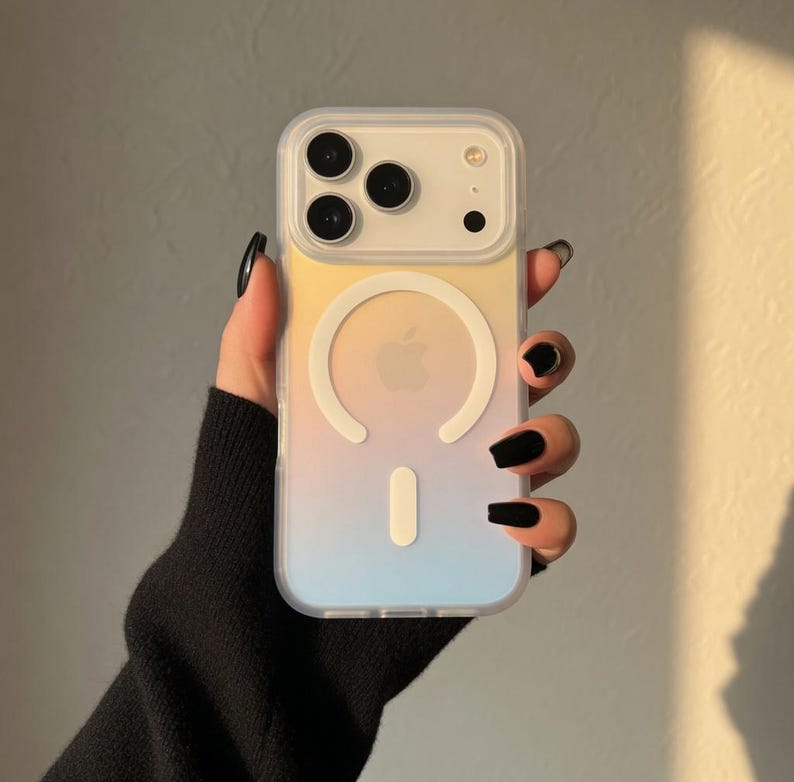 May include: A clear phone case with a gradient design of yellow, peach, and blue. The case has a white circular magnetic ring and a white vertical bar. The phone case has a camera cutout with three lenses.