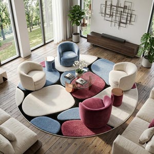May include: An overhead view of a modern living room with a large, round rug featuring a pattern of colorful, organic shapes. The room includes several curved armchairs in cream, blue, and burgundy, along with matching side tables and a glass coffee table.