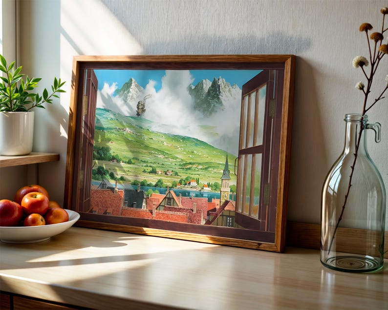 May include: A framed artwork depicts a scenic landscape viewed through an open window. The artwork showcases a village with red-tiled roofs, a church steeple, and mountains in the background. A glass bottle with a handle and a small plant are on the wooden surface.