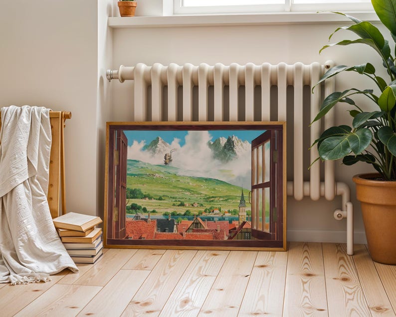 May include: A framed landscape painting depicts a view through an open window. The artwork showcases a green valley, a town with red-tiled roofs, and distant mountains under a cloudy sky. The frame is brown, and the painting is displayed indoors.