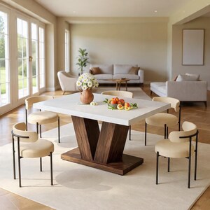 May include: A modern dining table with a white rectangular top and a dark brown wooden base. Six beige upholstered chairs with black metal frames surround the table. A vase of white flowers and a bowl of fruit are on the table.