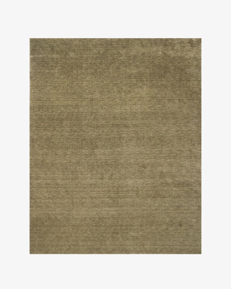 May include: A rectangular area rug featuring a solid, muted olive-green color with a subtle, horizontal, linear texture throughout the surface. The rug has a consistent, dense pile appearance that creates a soft, uniform look across the entire piece.