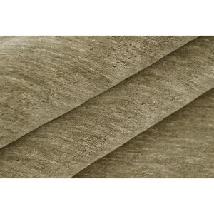 May include: A folded piece of fabric with a soft, textured surface in a muted taupe or light brown color. The material displays a dense, short pile with subtle variations in tone and light reflection across the overlapping layers of textile.