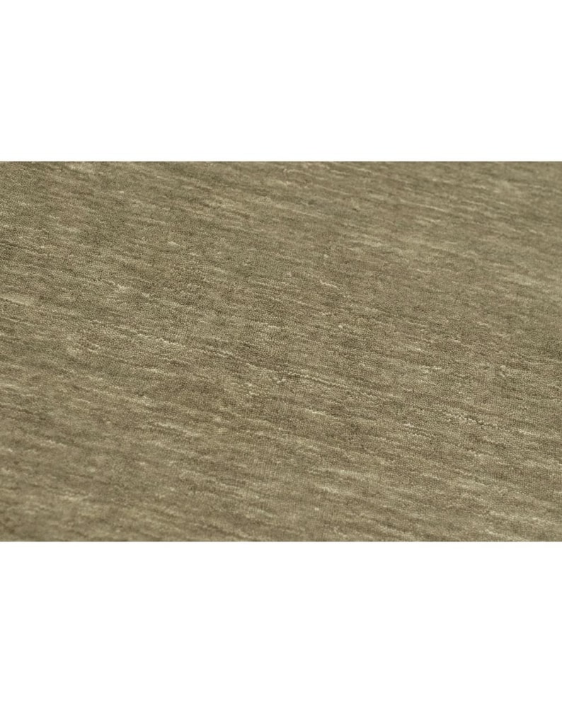 May include: A close-up view of a fabric surface featuring a heathered, taupe-colored textile. The material displays a subtle, horizontal grain with variations in tone, creating a soft, textured appearance across the entire visible area of the cloth.