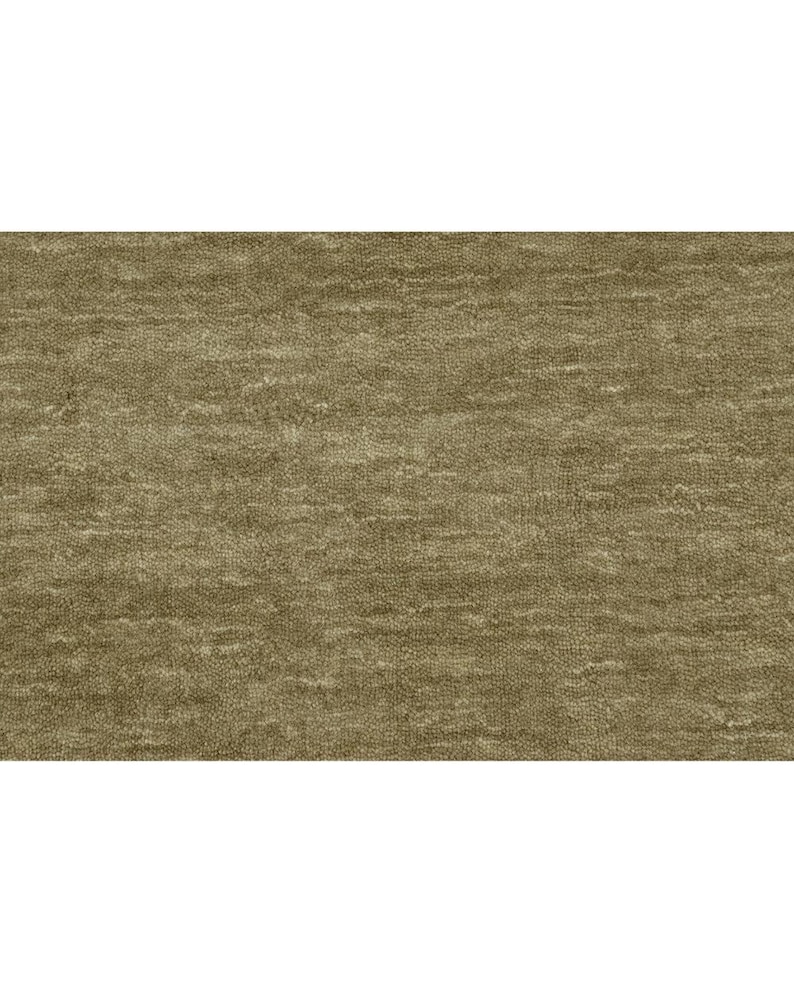 May include: A solid olive-brown textile fabric featuring a dense, short-pile surface with a subtle, horizontal, wavy texture pattern that creates a soft, light-reflecting appearance across the entire rectangular material surface.