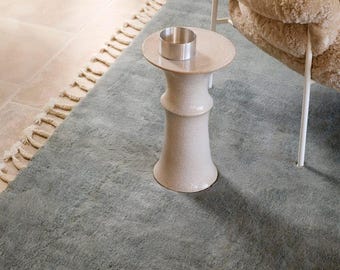 Alfombra de lana color salvia anudada a mano con flecos de borlas trenzadas.