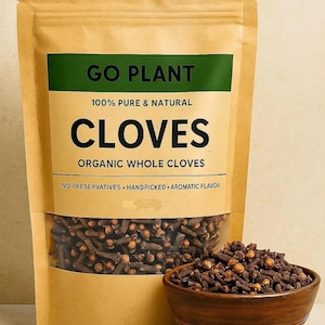 May include: A brown paper bag of organic whole cloves with a clear window, and a small wooden bowl filled with cloves. The bag has a green label with the text "GO PLANT" and "CLOVES". The text "100% PURE & NATURAL" is also visible.