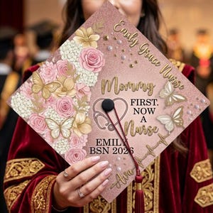 May include: A graduation cap with a pink glitter background, adorned with floral and butterfly designs. The cap features the text "Mommy First, Now a Nurse" and the name "Emily Grace Nurse" along with the year "2026". A stethoscope and heart are also included.