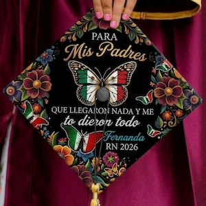 May include: Black graduation cap decorated with a butterfly design in the colors of the Mexican flag. The cap features floral accents and text that reads "PARA Mis Padres" and "QUE LLEGARON NADA Y ME to dieron todo Fernanda RN 2026."