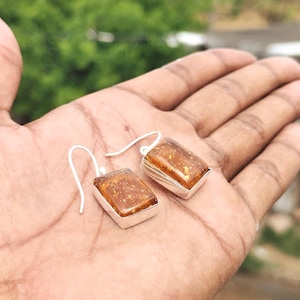 Könnte beinhalten: Eine weiße Keramik-Tasse mit schwarzem Henkel und dem Text "But First, Coffee" in handschriftlichem Stil. Die Tasse steht auf einer weißen Oberfläche. Die Tasse ist etwa 10 cm hoch.