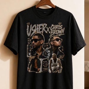 May include: Black t-shirt featuring a graphic design with the text "USHER x CHRIS BROWN" and images of the artists. The design includes rhinestone accents and additional text and images.