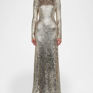 Könnte beinhalten: Ein bodenlanges Kleid mit langen Ärmeln, bedeckt mit goldenen Pailletten. Das Kleid hat einen hohen Ausschnitt und eine figurbetonte Silhouette, die sich am Saum leicht ausstellt. Die Pailletten erzeugen einen schimmernden Effekt.