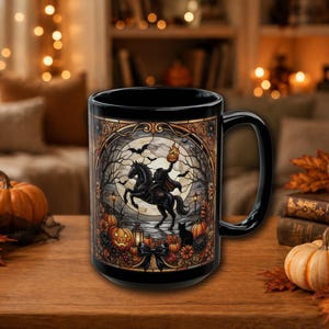 Puede incluir: Una taza de cerámica negra con una ilustración detallada de un jinete sin cabeza montando un caballo bajo una luna llena, rodeado de calabazas, murciélagos y un gato negro, todo enmarcado dentro de un borde decorativo estilo vitral.