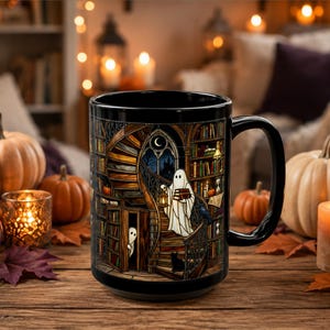 May include: A black ceramic mug featuring a detailed illustration of a library with a spiral staircase, bookshelves, a ghost holding a lantern and books, a smaller ghost peeking from a doorway, a black cat, and a raven under a crescent moon.